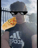 a man wearing sunglasses is holding a burrito