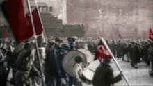 a crowd of people holding red flags in front of a pyramid