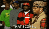 a group of men are standing in a line and one of them is holding a red cup and says `` that score ... '' .