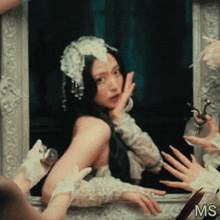 a woman in a white dress is looking at herself in the mirror