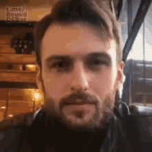 a man with a beard is wearing headphones and looking at the camera in a restaurant .