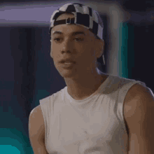 a man wearing a white tank top and a black and white checkered hat