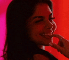 a woman is smiling with her hand on her face .