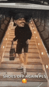 a man is walking down a set of stairs holding a bag and a hat .