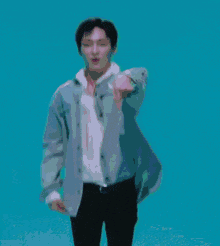a man in a denim jacket and tie is dancing on a blue background