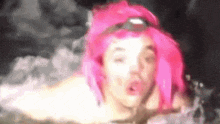 a blurry picture of a woman with pink hair blowing a kiss
