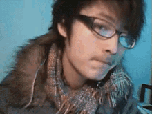 a man wearing glasses and a scarf is looking at the camera