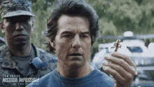 a man in a blue shirt is holding a cross in his hand .