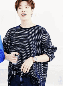 a man wearing a polka dot shirt and a watch holds a glass
