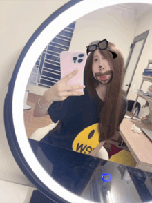 a woman taking a selfie in front of a mirror wearing a shirt that says we on it