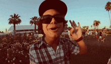 a man wearing sunglasses and a hat is making a peace sign