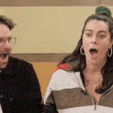 a woman with a surprised look on her face is sitting next to a man
