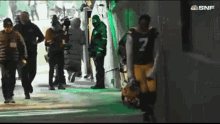 a football player with the number 7 on his jersey walks through a tunnel