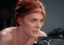 a man with red hair is holding a gun in his hand .