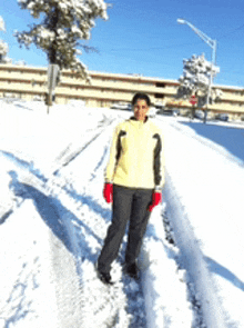 a woman wearing a yellow jacket and red gloves is standing in the snow