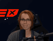 a woman wearing glasses and headphones stands in front of a microphone with the letter x in the background