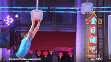 a man in a blue shirt is jumping over a basketball hoop with the number 16 on it ..
