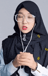a woman wearing a hijab and glasses has the number 6 on her sleeve
