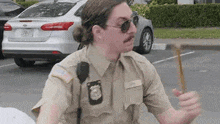 a police officer is standing in a parking lot holding a baton .