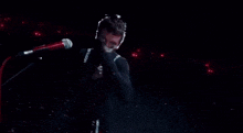a man is singing into a microphone in a dark room .
