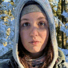 a woman wearing a hooded jacket and a beanie is standing in the snow