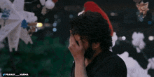 a man covering his face in front of a christmas tree with the words pranay_varma below him