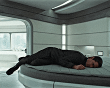 a man is laying on a round bed with his head on the mattress