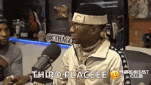 a man wearing a gucci headband is sitting in front of a microphone .