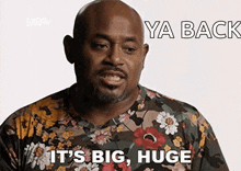 a bald man wearing a floral shirt says " it 's big huge "