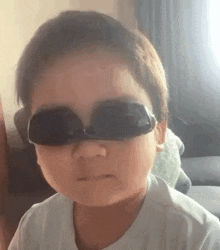 a young boy wearing sunglasses is making a face .