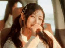 a young woman singing into a microphone in a car