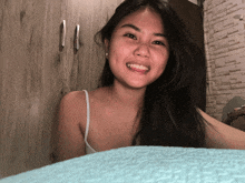 a woman is smiling in front of a wooden cabinet