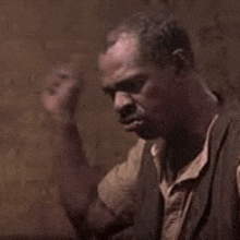 a man is sitting in front of a wall with his fist up .