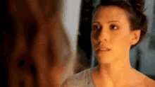 a woman is looking at her face in a mirror .