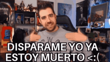 a man with a beard is giving a thumbs up in front of a sign that says disparame yo ya estoy muerto <
