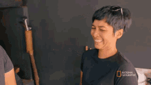 a woman wearing a national geographic t-shirt is smiling