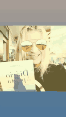 a woman wearing sunglasses is holding a book that says ' orisici ' on the cover