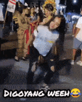 a woman is dancing in front of a crowd with the words digoyang weeh below her