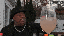 a man wearing a top hat is holding a large glass of liquid