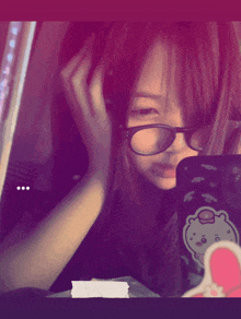 a girl wearing glasses looks at her phone