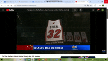 a computer screen shows a video of shaq 's # 32 jersey hanging from the rafters