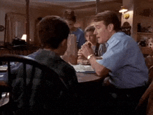 a man and two children are sitting at a table eating a sandwich .