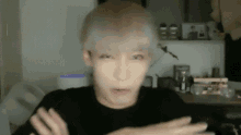 a man with blonde hair is making a funny face with his hands