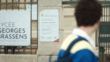 a man walking in front of a sign that says lycee georges brassens