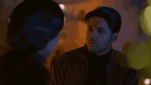 a man and woman are looking at each other in the dark