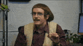 a man with glasses and a moustache is sitting in front of a laptop