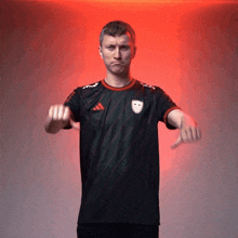 a man wearing an adidas shirt is making a thumbs down gesture