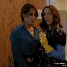 two women are standing next to each other and one is wearing a yellow glove