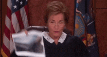 a female judge is holding a piece of paper in front of her .