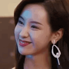 a close up of a woman 's face with a smile on her face and earrings .